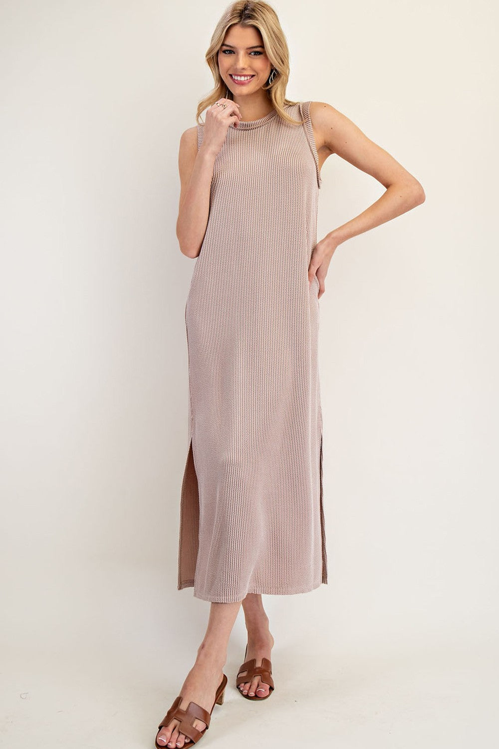woman wearing a beige ribbed maxi dress with side slits and smiling while posing