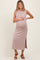 woman wearing a blush ribbed maternity dress with a side slit and holding her baby bump