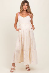 woman wearing a cream maternity maxi dress with pink floral patterns and pockets, showing her baby bump