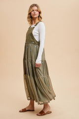 woman wearing an olive green tiered maxi dress with embroidered flowers over a white long sleeve top and sandals