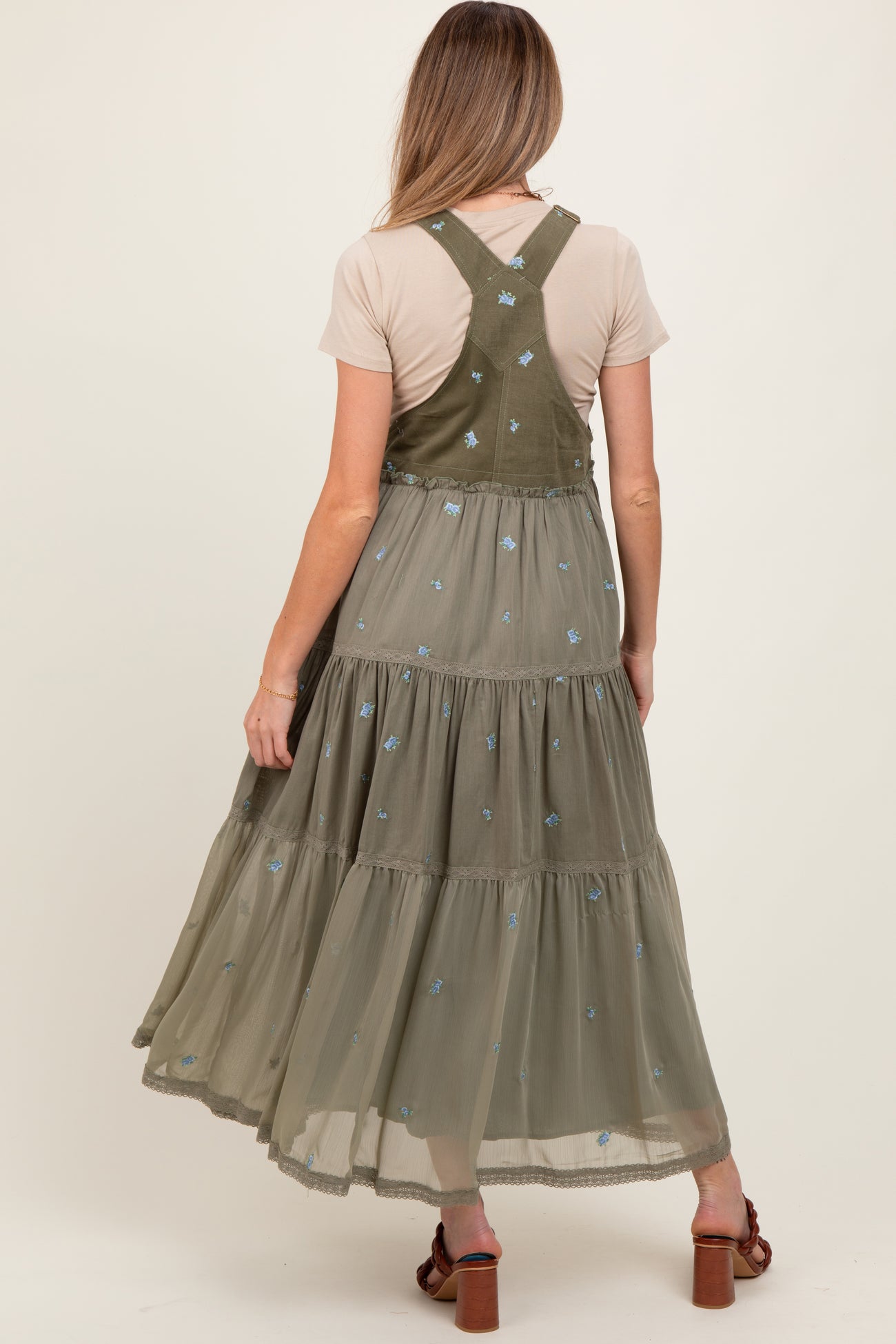 woman wearing a green embroidered maternity maxi dress with a tiered skirt and spaghetti straps