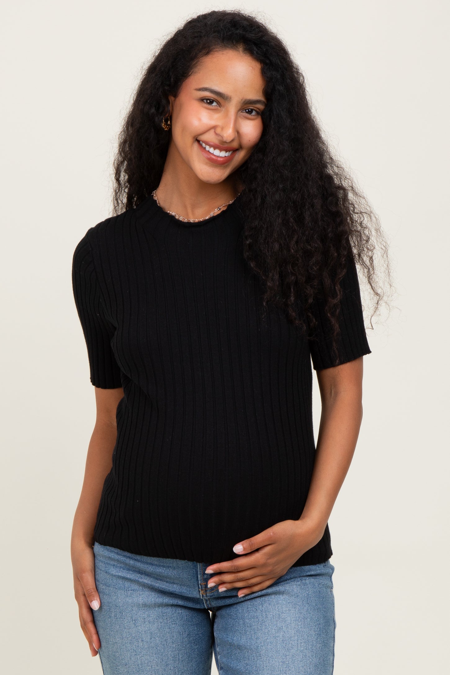 woman wearing a black ribbed short sleeve maternity top and holding her baby bump