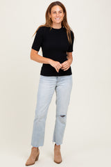 woman wearing a black ribbed short sleeve top and light blue distressed jeans with beige ankle boots
