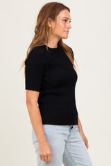woman wearing a black ribbed short sleeve top and light blue jeans