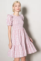 woman wearing a pink floral puff sleeve dress with a tiered skirt and smocked bodice