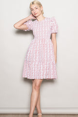 woman wearing a pink floral print dress with puff sleeves and a tiered skirt