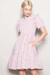 woman wearing a pink floral print puff sleeve dress with a tiered skirt and pockets