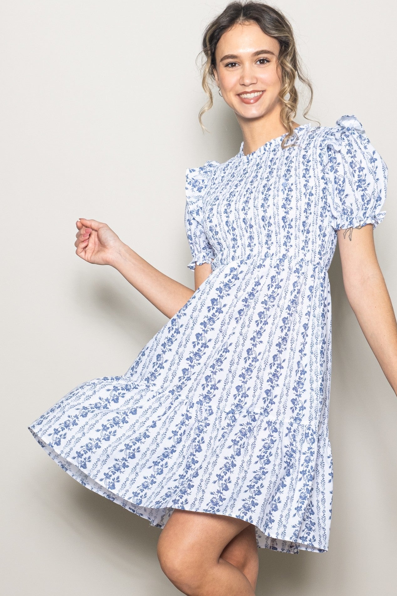 woman wearing a blue and white floral print short sleeve dress with a tiered skirt and puffed sleeves