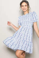 woman wearing a blue and white floral print short sleeve dress with a tiered skirt and puffed sleeves