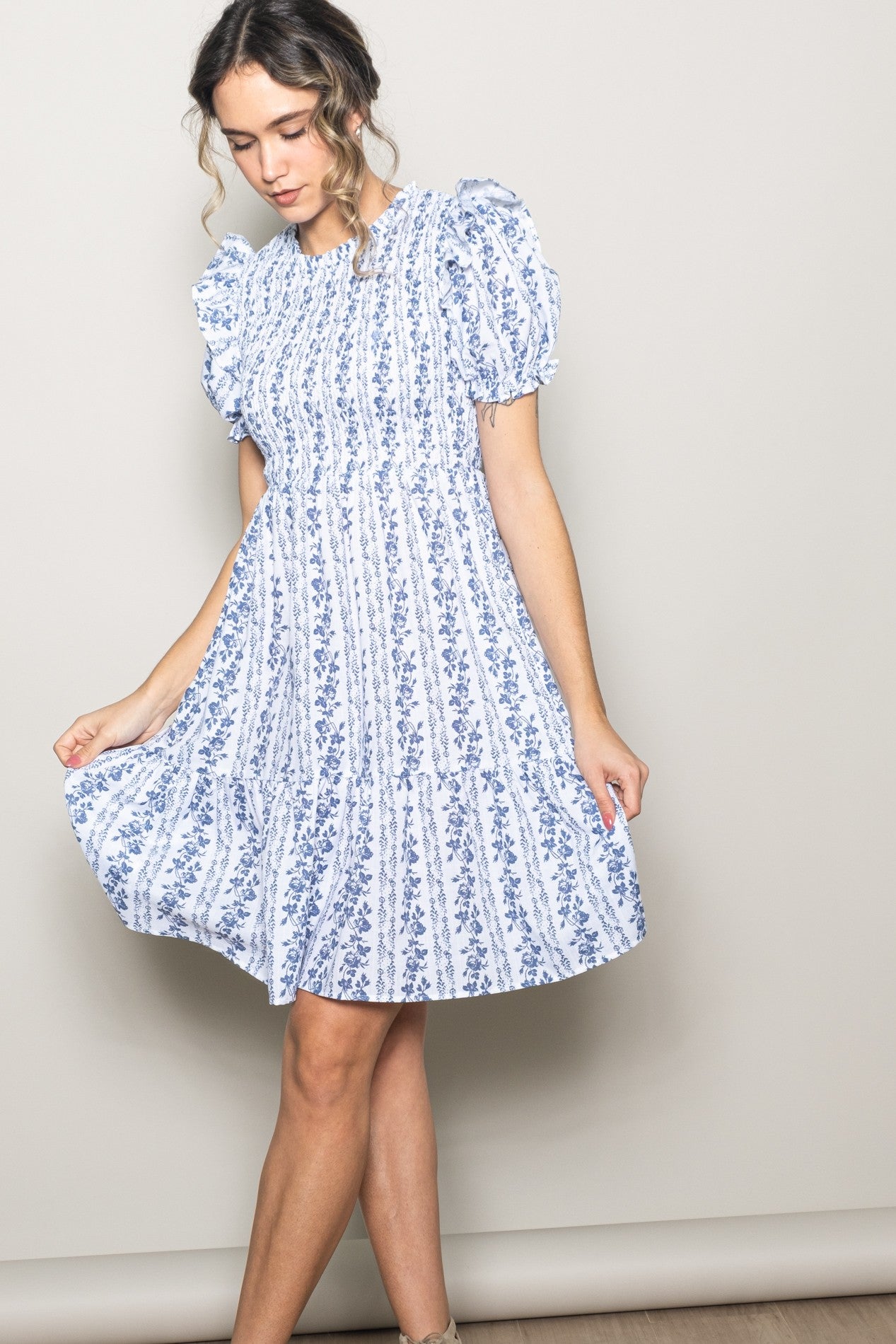 woman wearing a blue and white floral mini dress with puff sleeves and a tiered skirt