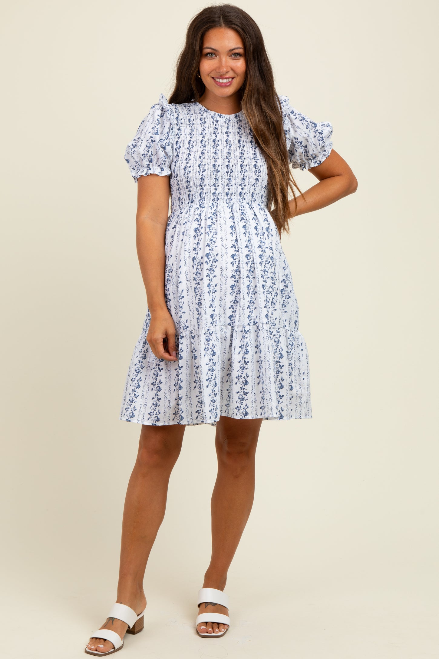 woman wearing a blue and white floral maternity dress with puff sleeves and a tiered skirt