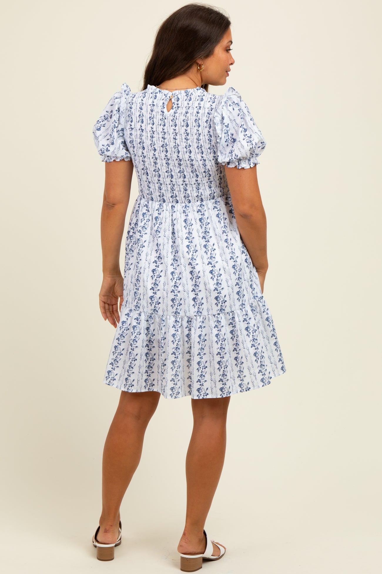 woman wearing a floral print maternity dress with puff sleeves and a tiered skirt, showing off her baby bump