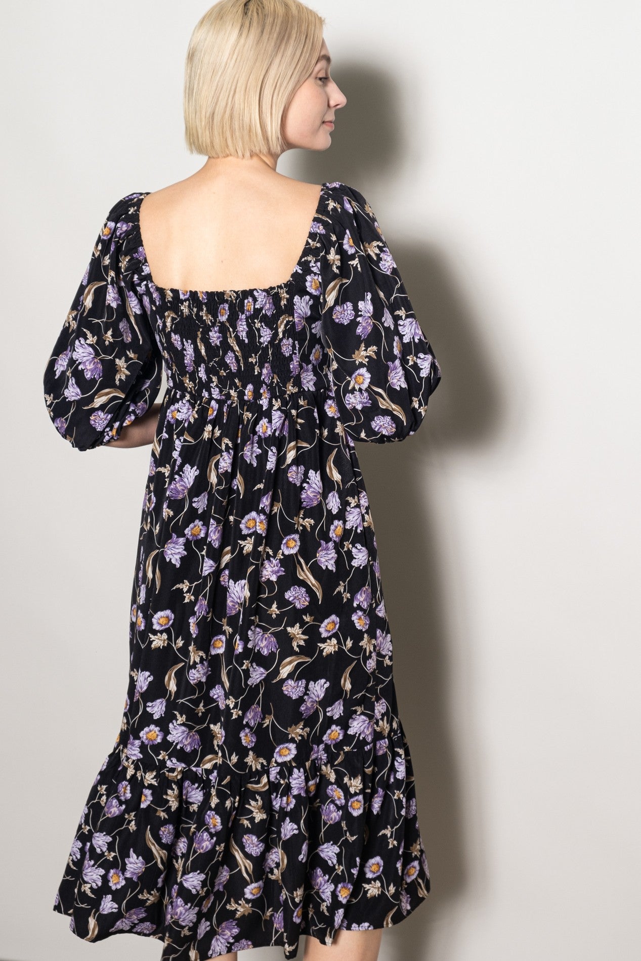 woman wearing a black floral midi dress with puff sleeves and a smocked back detail