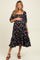 woman wearing a black floral maternity dress with a ruffled hem and gathered bust, holding her baby bump