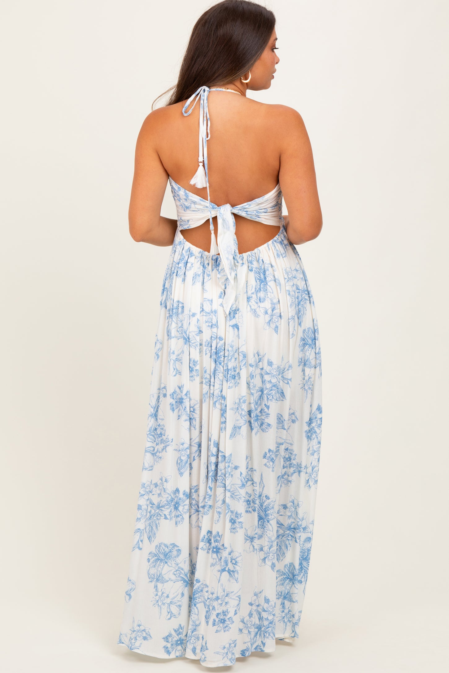 woman wearing a floral print maternity maxi dress with a halter neck and open back design
