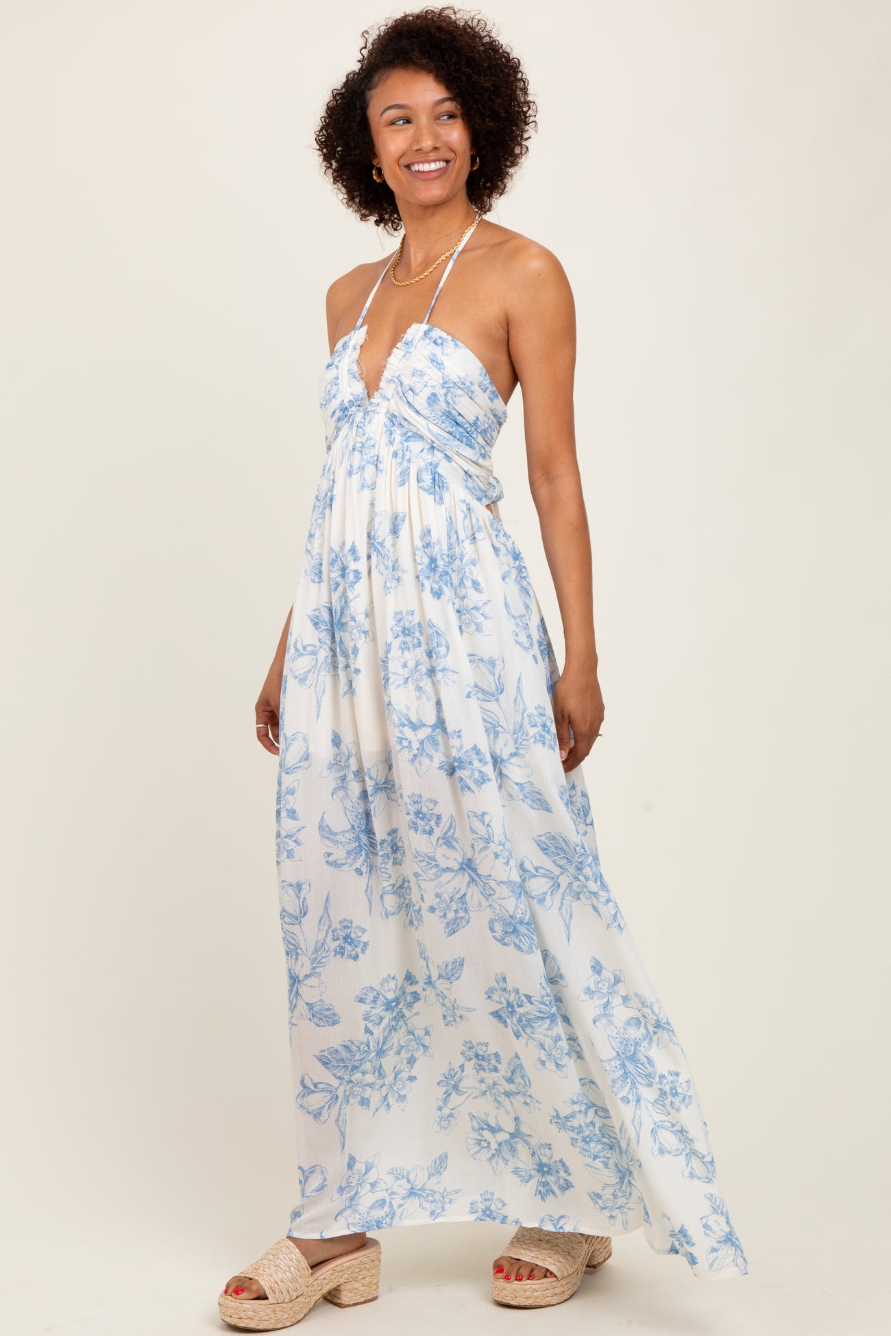 woman wearing a white floral maxi dress with blue prints and a halter neck style