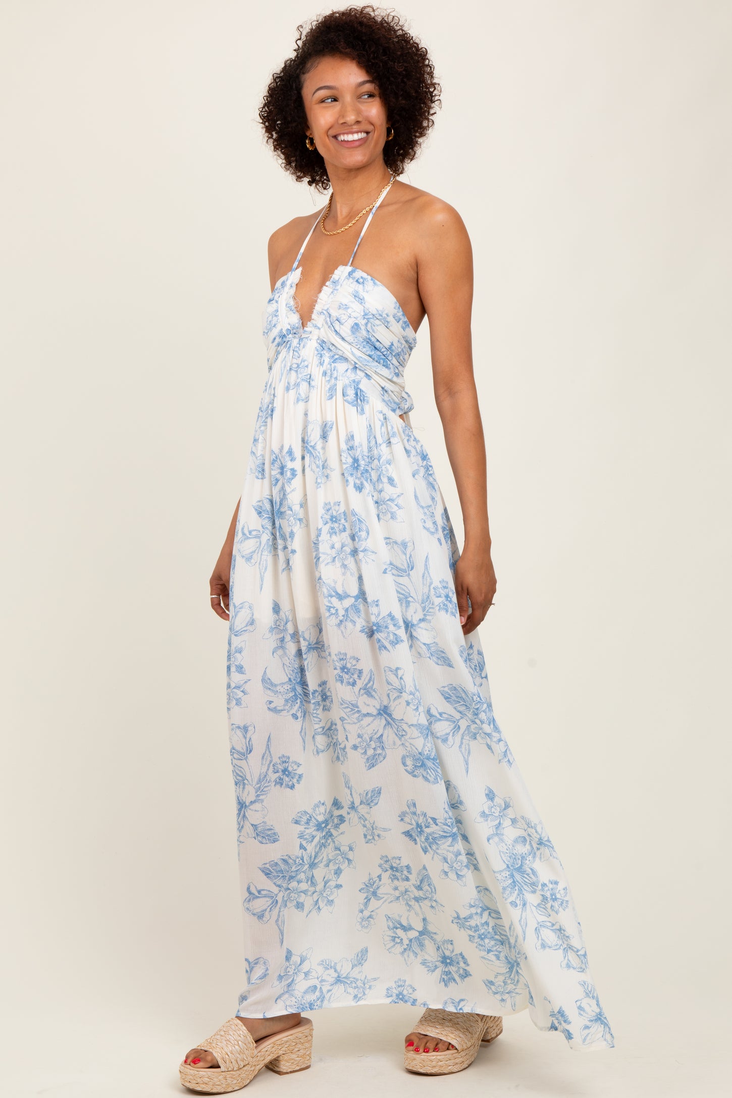 woman wearing a white floral maxi dress with blue prints and a halter neck style