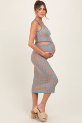 woman wearing a multicolored wave pattern maternity set with a fitted tank top and long skirt, cradling her baby bump