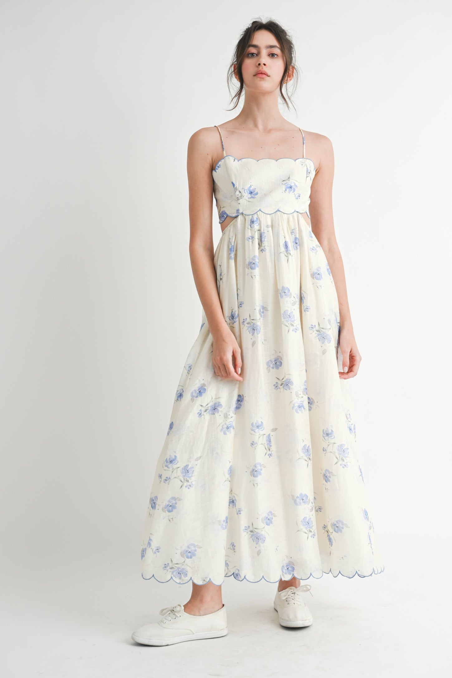 woman wearing a floral print maxi dress with spaghetti straps and a scalloped neckline