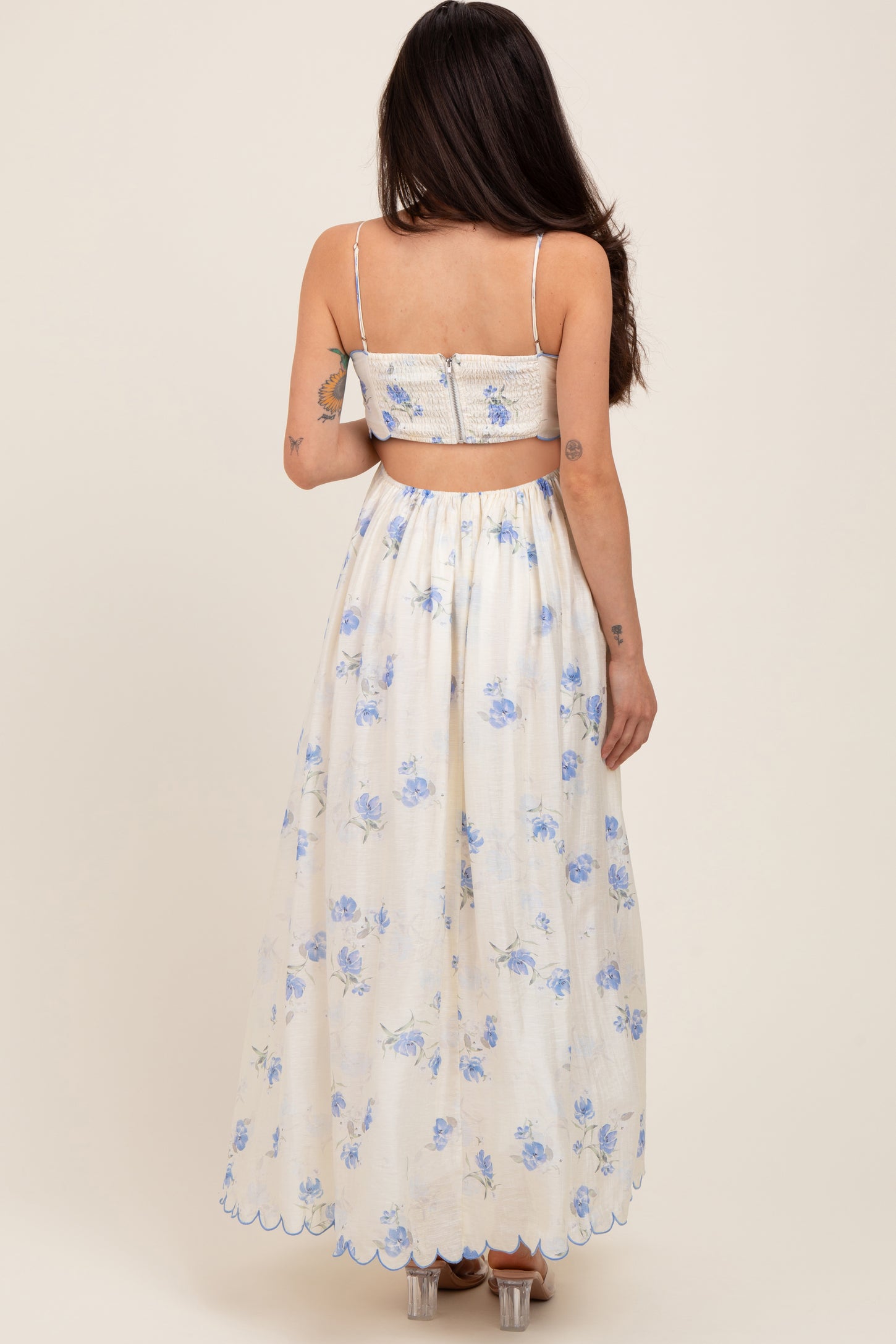 woman wearing a white floral maternity maxi dress with a backless design and blue flower patterns