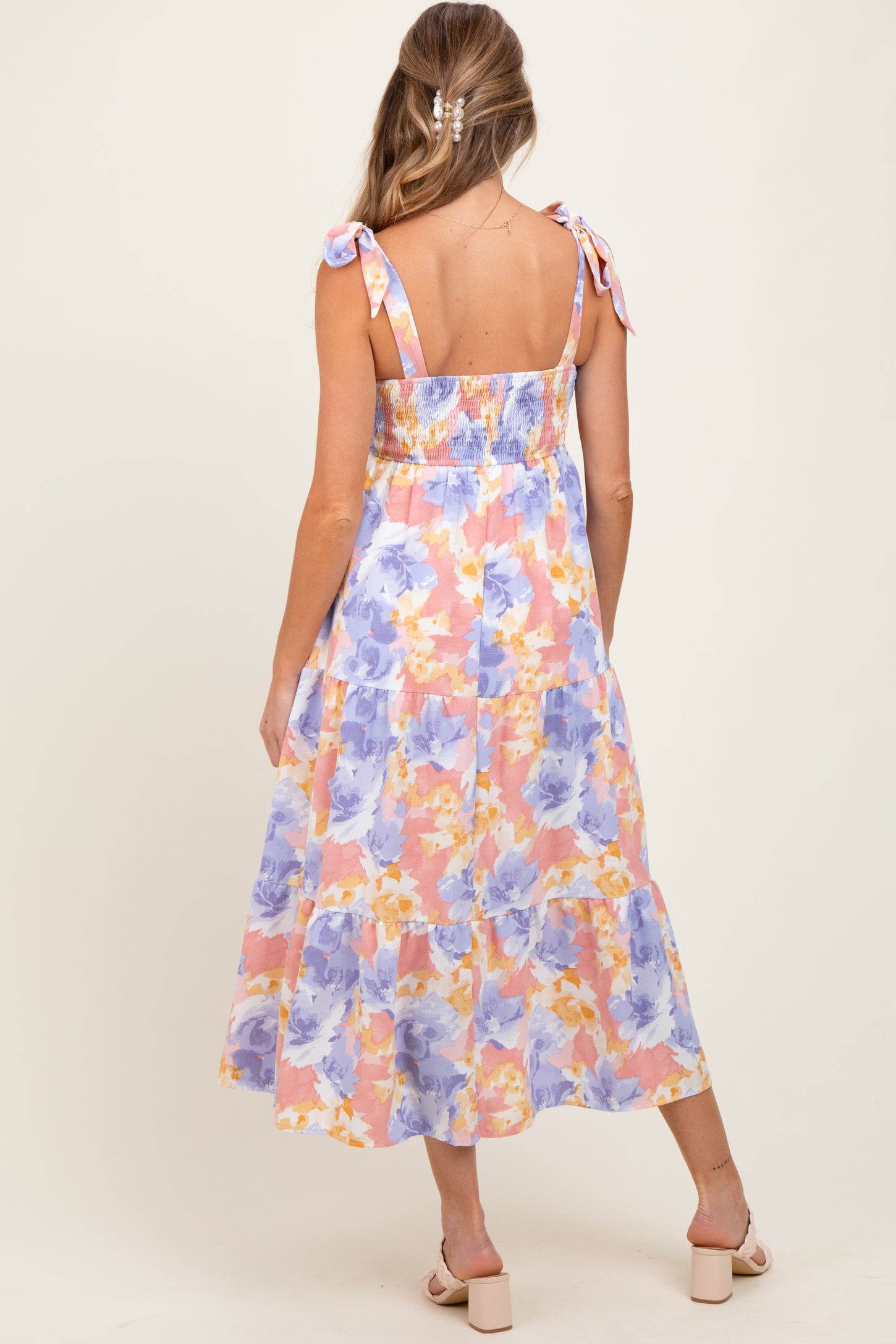 woman wearing a floral maternity dress with adjustable tie straps and a smocked back, showcasing a flowing skirt