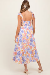 woman wearing a floral maternity dress with adjustable tie straps and a smocked back, showcasing a flowing skirt