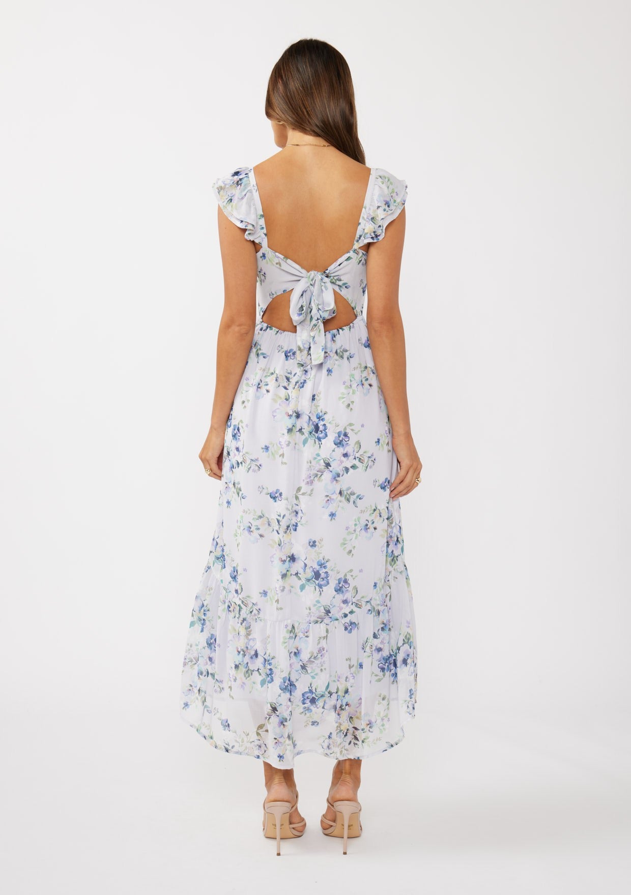 woman wearing a floral maxi dress with ruffled sleeves and a tie-back detail, showing skin at the back