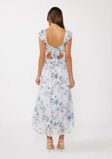 woman wearing a floral maxi dress with ruffled sleeves and a tie-back detail, showing skin at the back