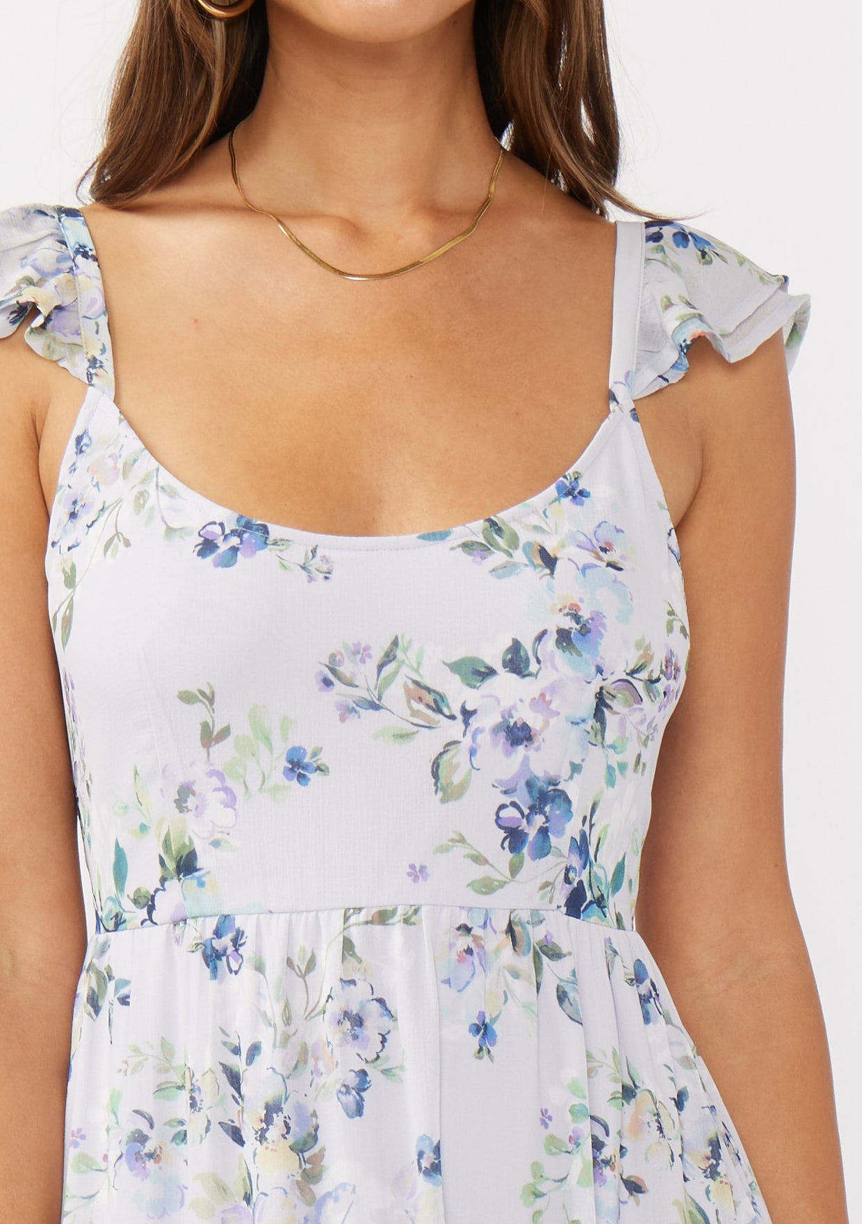 woman wearing a light floral print dress with ruffle straps and a square neckline