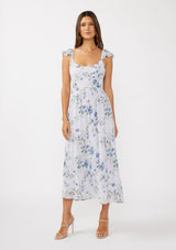 woman wearing a white floral maxi dress with ruffled straps and a flowing silhouette