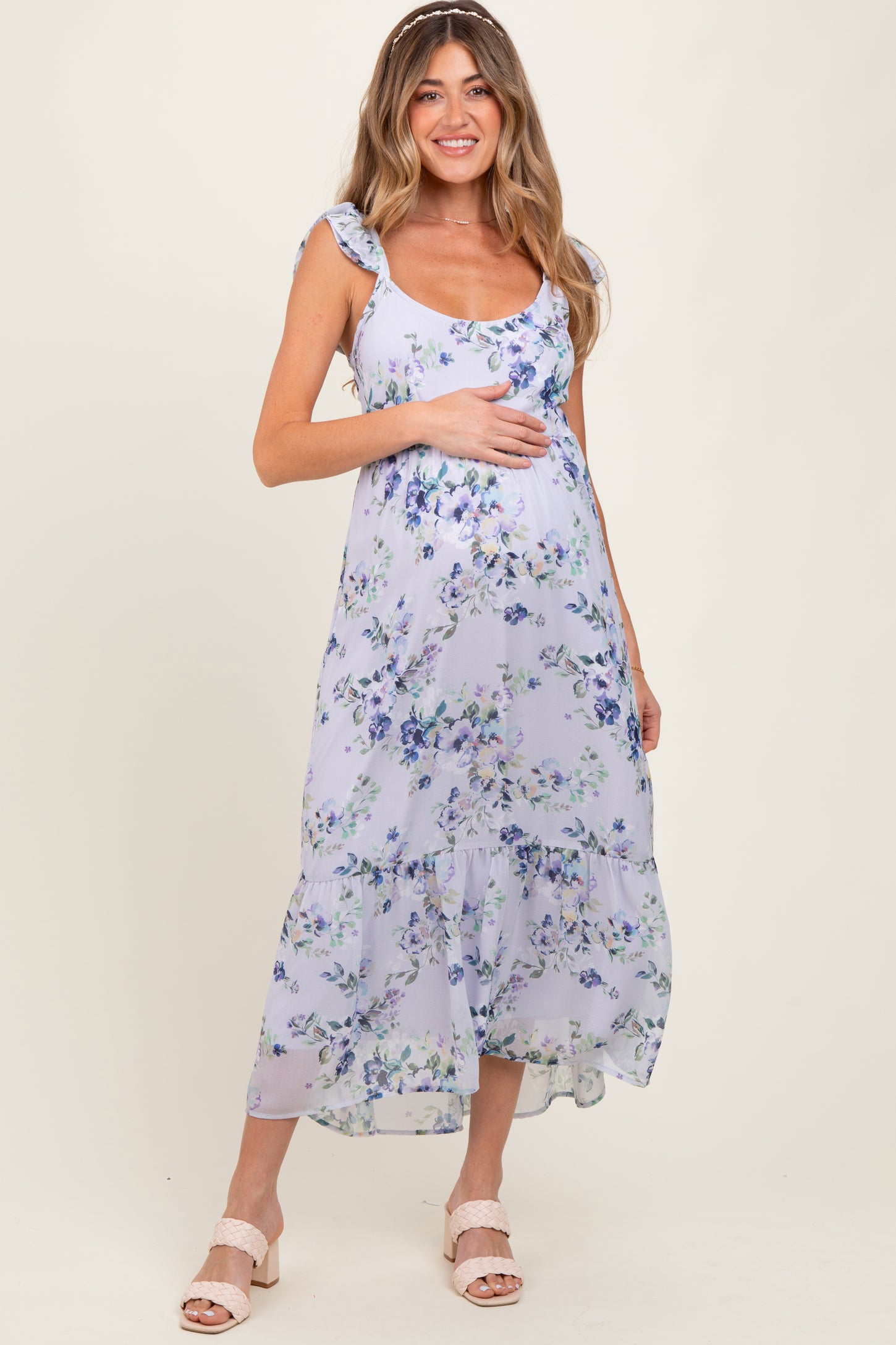 woman wearing a floral lavender maternity dress and holding her baby bump