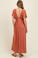 woman wearing a rust colored maternity maxi dress with an open back and short sleeves