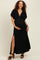 woman wearing a black maternity maxi dress with a deep v-neck and side slit, cradling her baby bump