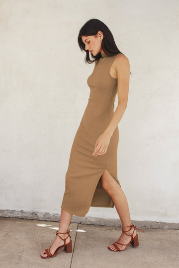 woman wearing a beige ribbed midi dress with a side slit and strappy brown heels