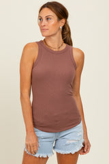 woman wearing a brown ribbed tank top and denim cut-off shorts, standing with a relaxed expression