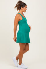 woman wearing a green maternity dress with a flared skirt and holding her baby bump