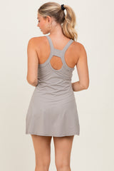 woman wearing a gray racerback sports dress with a flared skirt and cut-out detail on the back