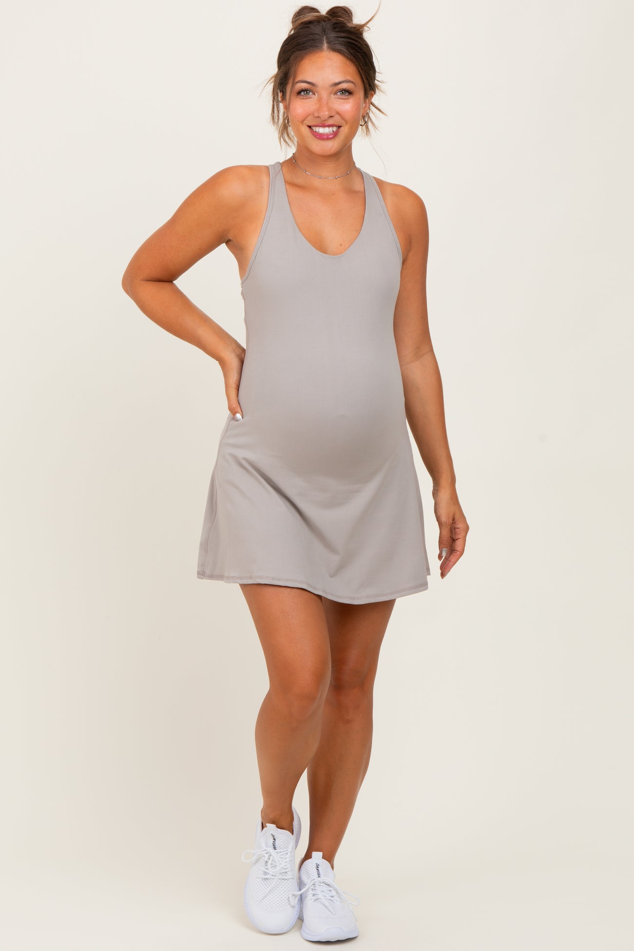 woman wearing a gray sleeveless maternity dress with a v-neck and visible baby bump