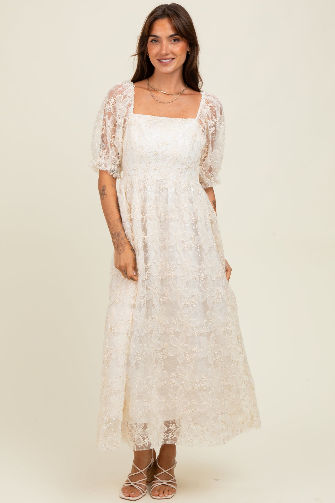 woman wearing a white floral lace maxi dress with puff sleeves and a square neckline