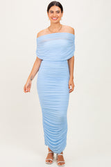 woman wearing a light blue off-shoulder ruched maxi dress with a fitted silhouette and strappy heels