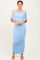 woman wearing a light blue off-shoulder ruched maxi dress standing against a neutral background