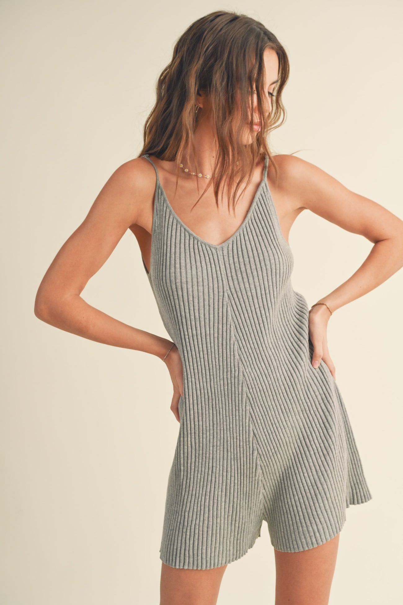 woman wearing a light gray ribbed tank romper with a v-neck and fitted silhouette
