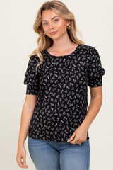 woman wearing a black floral print short sleeve top with puff sleeves and styled with light blue jeans