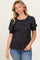 woman wearing a black floral print short sleeve top with puff sleeves and styled with light blue jeans