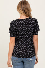 woman wearing a black floral short sleeve top with puffed sleeves, styled with blue jeans, view from the back