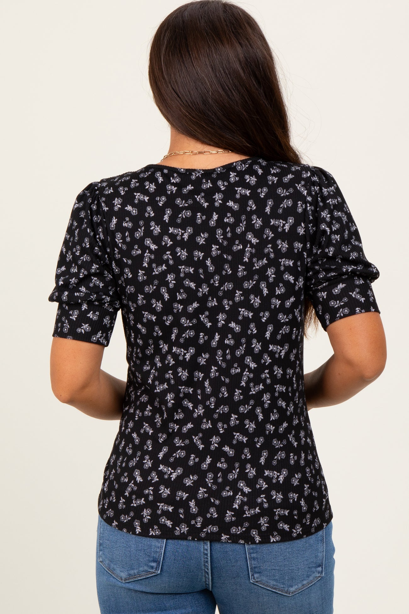 woman wearing a black maternity top with floral print and short puff sleeves, seen from the back