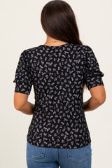 woman wearing a black maternity top with floral print and short puff sleeves, seen from the back