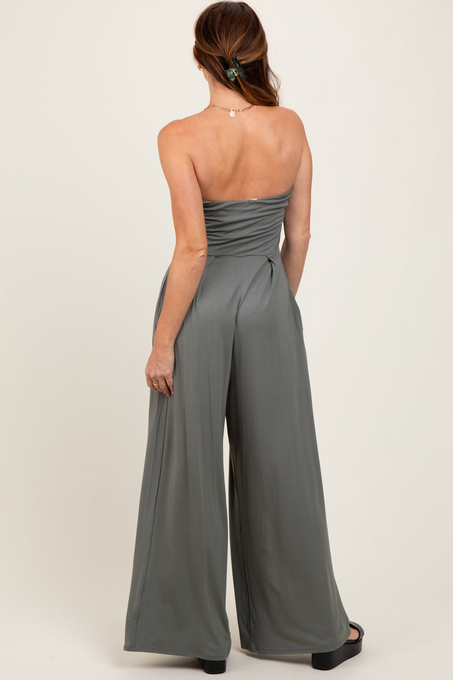 woman wearing a backless olive green strapless jumpsuit with wide-leg pants