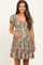woman wearing a green floral maternity dress with puff sleeves and a baby bump visible
