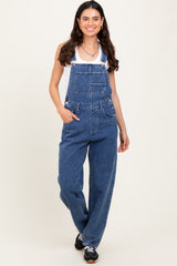 woman wearing a white tank top and blue denim overalls with a relaxed fit and front pockets